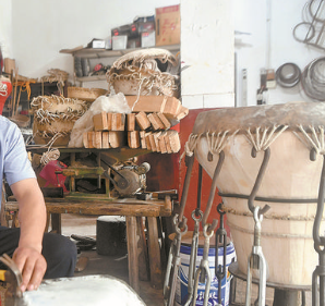 匠人用機(jī)械千斤頂固定做皮鼓的牛皮